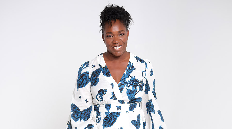 Photo of Alexandra Kane wearing a white dress with black and blue details, standing in front of a white background.