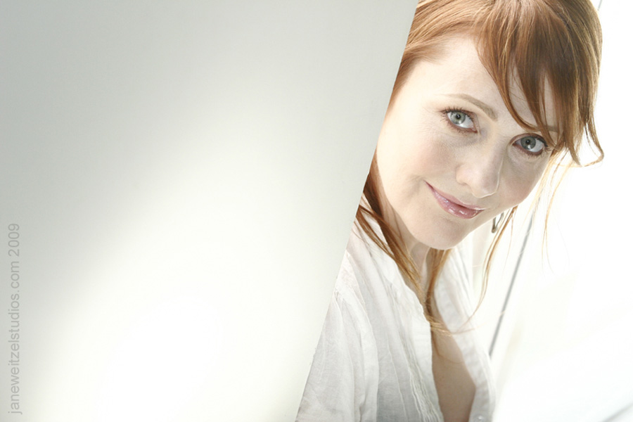 Photo of playwright Trina Davies, wearing a white shirt and posing against a white backdrop.