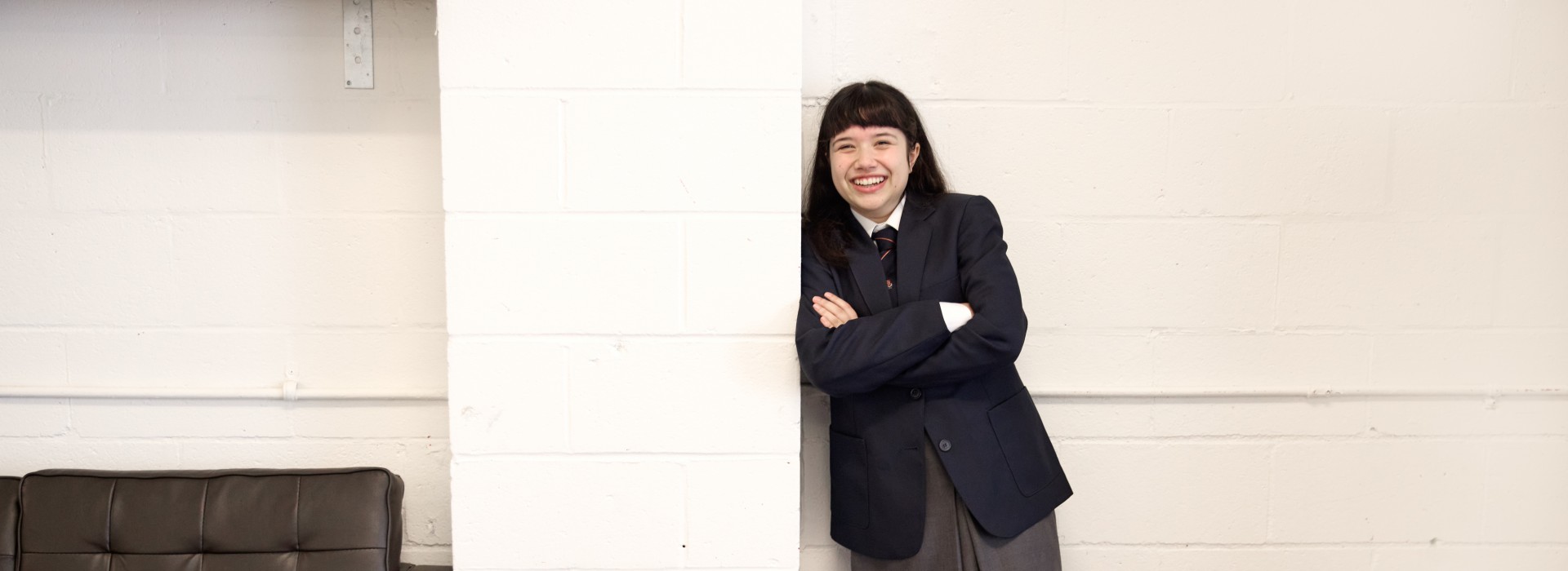 Neela Noble as Matilda, leaning against a brick wall.