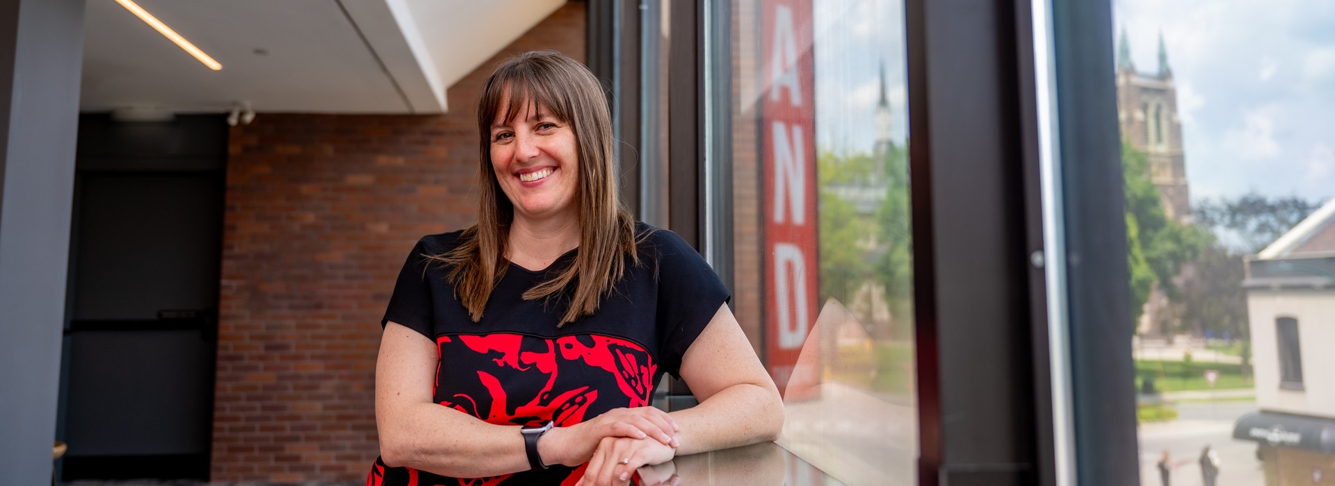 Lyndee Hansen stands in the Drewlo Lounge, a view of downtown visible out the large Richmond Street windows.